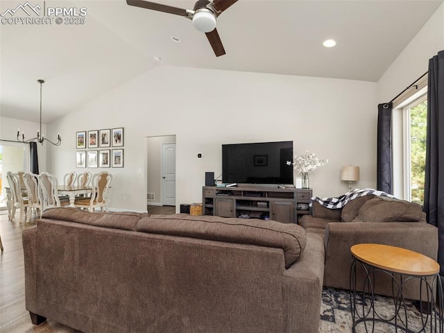 living room with ceiling fan with notable chandelier, light hardwood / wood-style flooring, and lofted ceiling