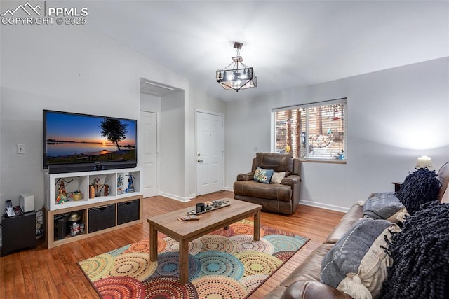 living room featuring hardwood / wood-style flooring, a chandelier, and lofted ceiling