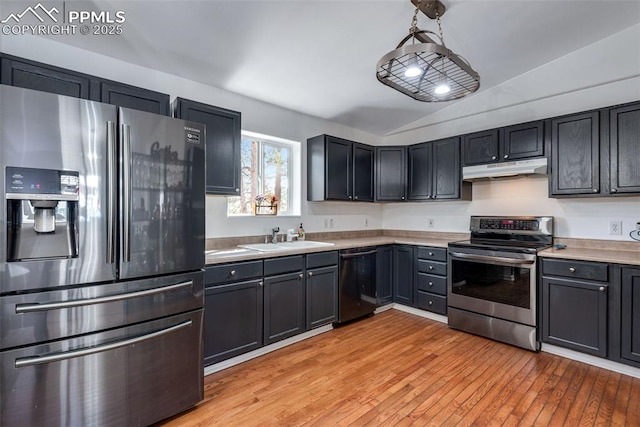 kitchen featuring appliances with stainless steel finishes, decorative light fixtures, sink, vaulted ceiling, and light hardwood / wood-style flooring