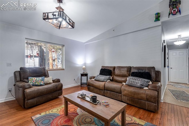 living room featuring a chandelier, lofted ceiling, and wood-type flooring