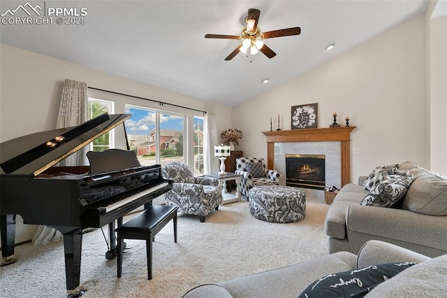 carpeted living room featuring a tiled fireplace, vaulted ceiling, and ceiling fan