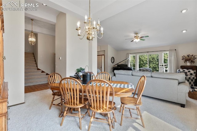 carpeted dining area featuring ceiling fan with notable chandelier