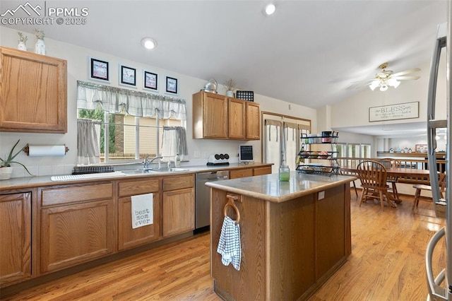 kitchen with dishwasher, sink, light wood-type flooring, a center island, and lofted ceiling