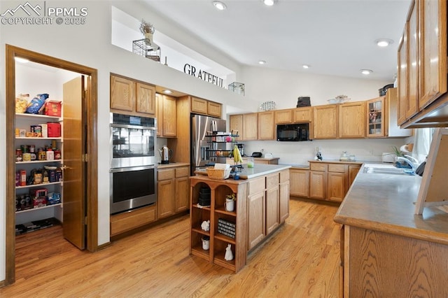 kitchen featuring a center island, stainless steel appliances, light hardwood / wood-style floors, sink, and high vaulted ceiling