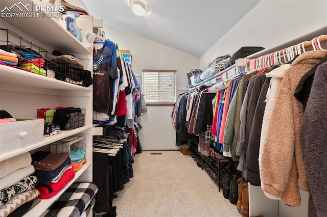 walk in closet with light colored carpet and lofted ceiling