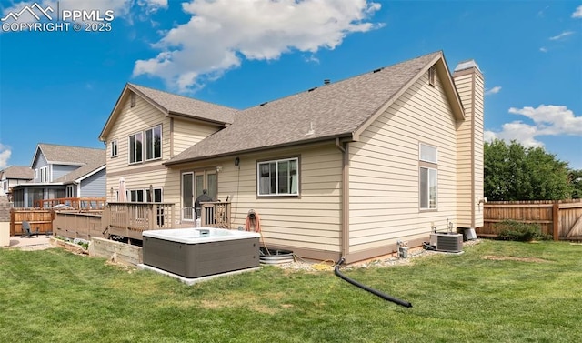 rear view of house featuring central AC unit, a wooden deck, a hot tub, and a yard