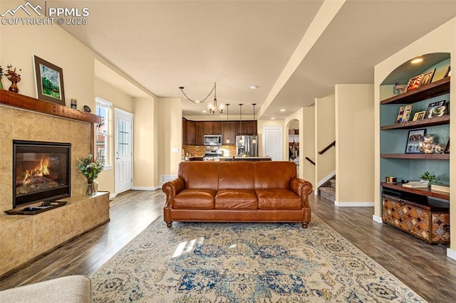 living room with an inviting chandelier, a high end fireplace, and dark wood-type flooring