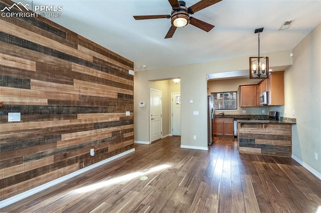 unfurnished living room with sink, wood walls, dark hardwood / wood-style floors, and ceiling fan