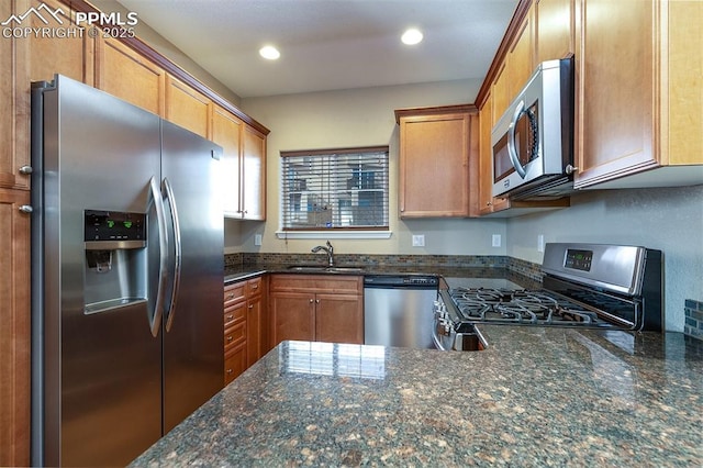 kitchen with sink, appliances with stainless steel finishes, and dark stone countertops