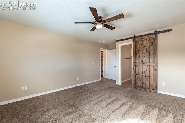 unfurnished bedroom featuring carpet, ceiling fan, and a barn door