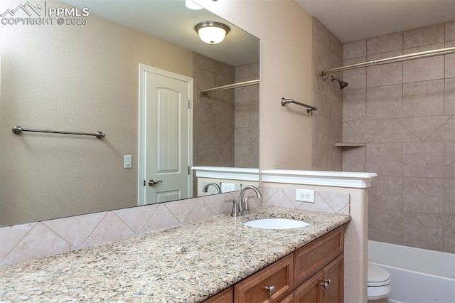 bathroom with toilet, vanity, and tasteful backsplash