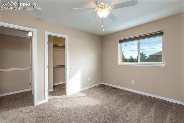 unfurnished bedroom with carpet flooring, a spacious closet, and ceiling fan