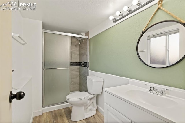 bathroom featuring wood-type flooring, vanity, an enclosed shower, and toilet