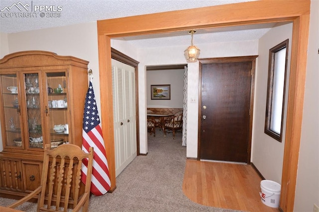 hall with light colored carpet and a textured ceiling