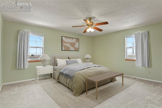 carpeted bedroom featuring multiple windows, a textured ceiling, and ceiling fan
