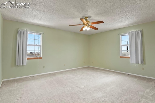 spare room with a wealth of natural light, light colored carpet, and ceiling fan