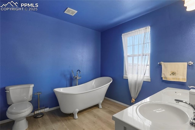 bathroom with wood-type flooring, toilet, vanity, and a tub
