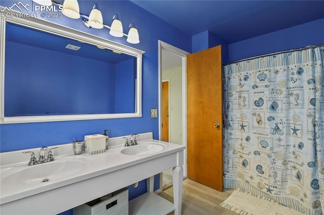 bathroom featuring hardwood / wood-style flooring and dual sinks