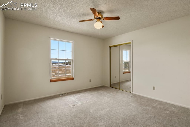 carpeted spare room with a textured ceiling and ceiling fan