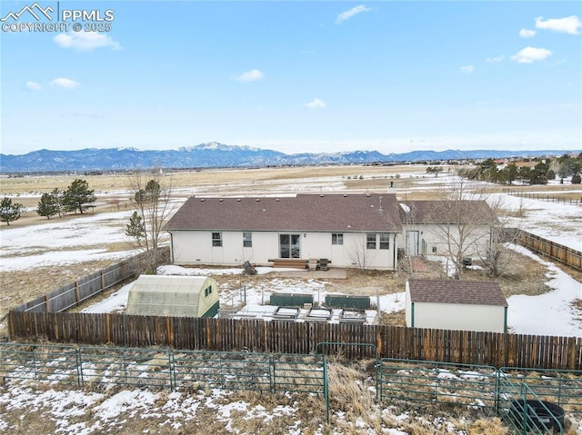 snow covered rear of property with an outdoor structure and a mountain view