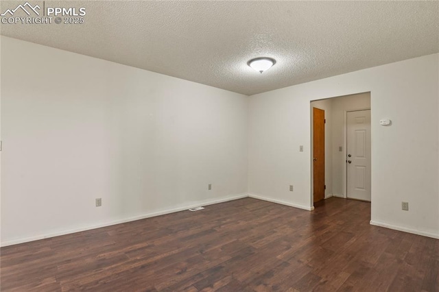 empty room with dark hardwood / wood-style floors and a textured ceiling