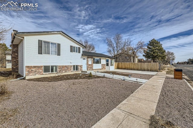 tri-level home featuring brick siding and fence