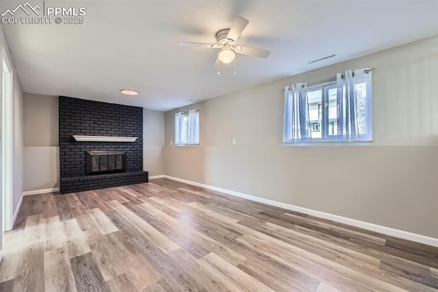 unfurnished living room with a brick fireplace, light hardwood / wood-style floors, and ceiling fan