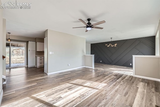 unfurnished living room with ceiling fan with notable chandelier and hardwood / wood-style floors