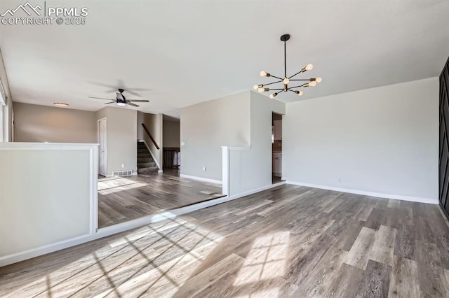 unfurnished living room with hardwood / wood-style flooring and ceiling fan with notable chandelier