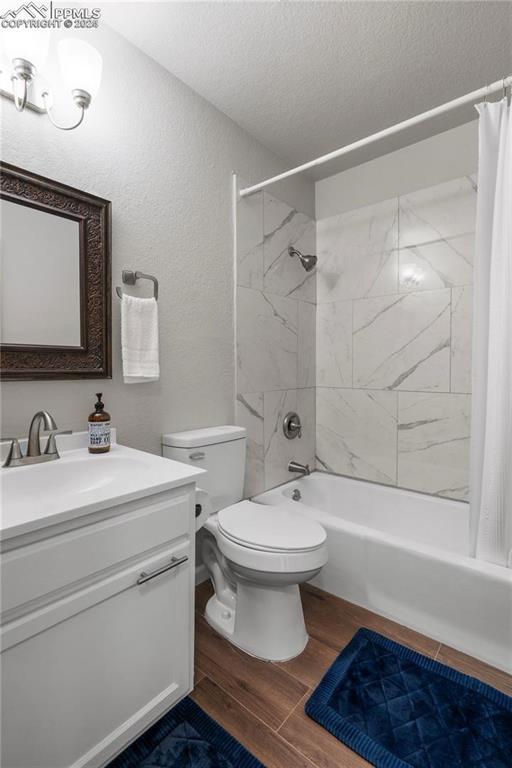 full bathroom with toilet, vanity, shower / bathtub combination with curtain, and a textured ceiling