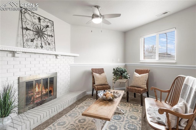 living area with ceiling fan, a brick fireplace, and carpet