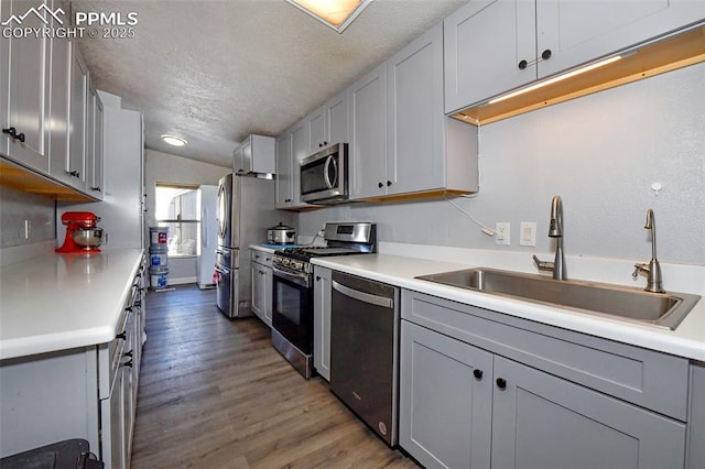 kitchen featuring stainless steel appliances, sink, a textured ceiling, and gray cabinets