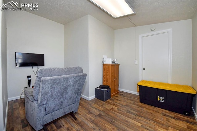 living area with dark wood-type flooring and a textured ceiling