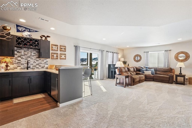 interior space featuring sink, a kitchen breakfast bar, kitchen peninsula, carpet floors, and backsplash