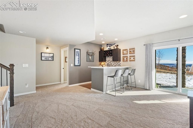 kitchen with light colored carpet, decorative backsplash, a kitchen breakfast bar, and kitchen peninsula