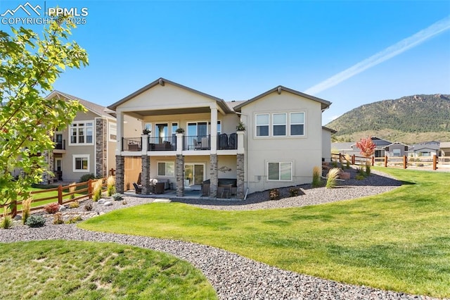 rear view of house with a mountain view, a lawn, and a balcony