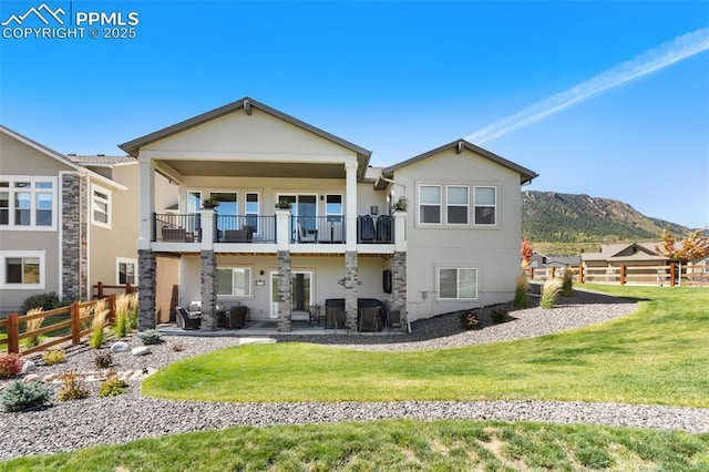 back of property featuring a balcony, a yard, a mountain view, and a patio area