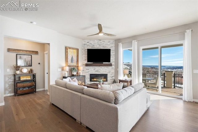 living room with hardwood / wood-style floors, a stone fireplace, and ceiling fan