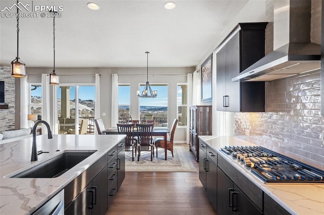 kitchen with appliances with stainless steel finishes, decorative light fixtures, sink, and wall chimney range hood