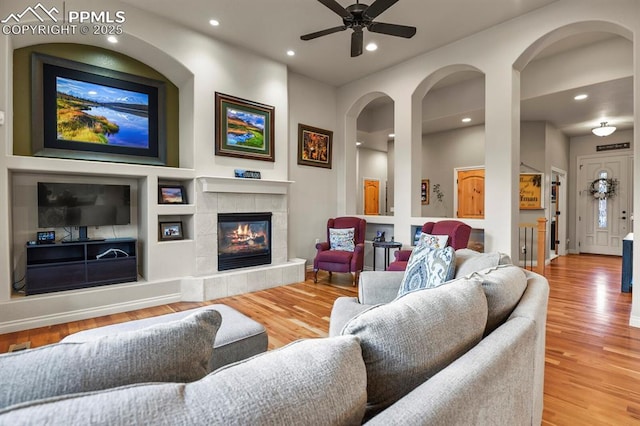 living room featuring ceiling fan, hardwood / wood-style floors, and a tile fireplace