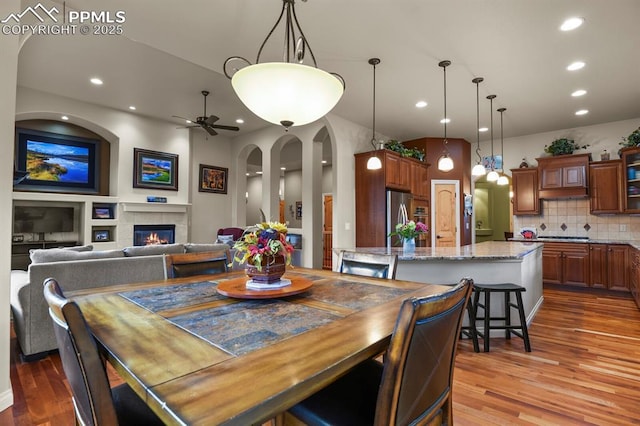 dining space with a fireplace, ceiling fan, and dark hardwood / wood-style flooring