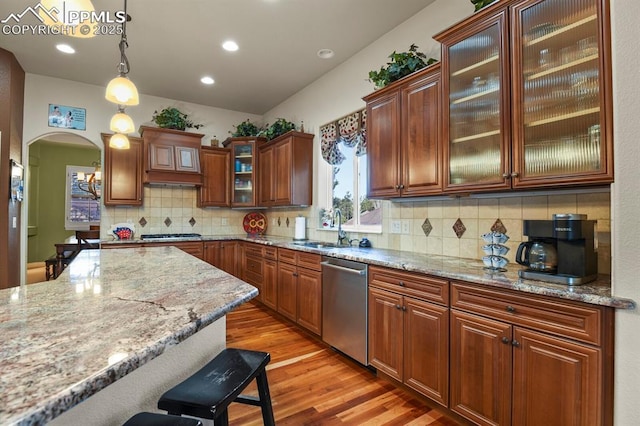 kitchen featuring light stone countertops, decorative light fixtures, stainless steel appliances, sink, and a breakfast bar area