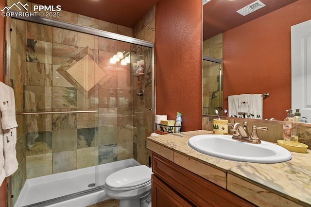 bathroom featuring vanity, toilet, and a shower with door