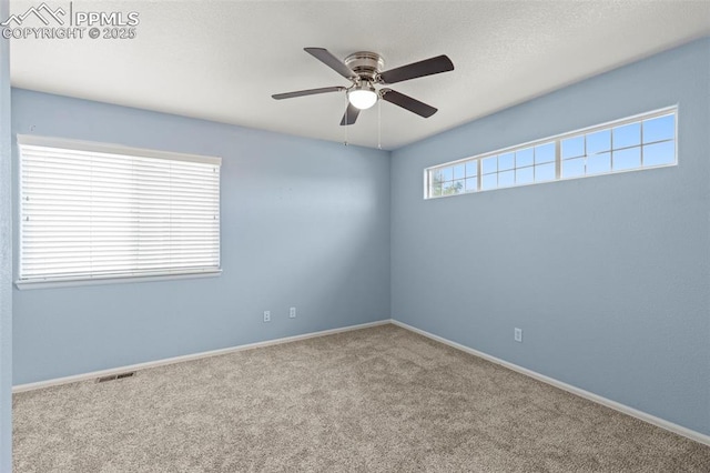 spare room featuring light carpet, ceiling fan, and a wealth of natural light