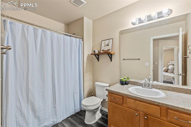 bathroom featuring hardwood / wood-style floors, toilet, vanity, and a textured ceiling