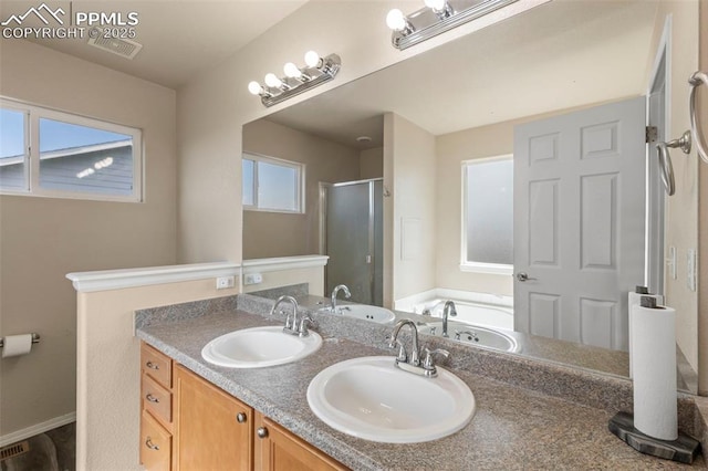 bathroom featuring a healthy amount of sunlight, separate shower and tub, and vanity