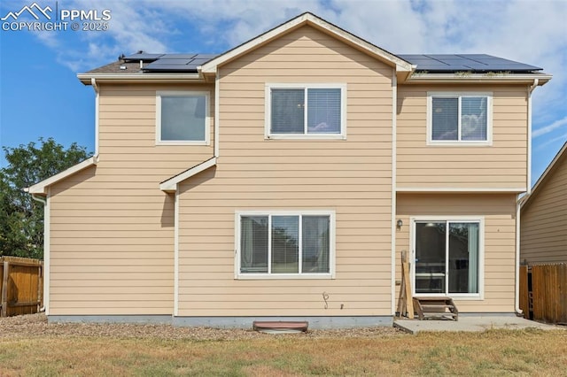 rear view of house featuring a lawn, solar panels, and a patio