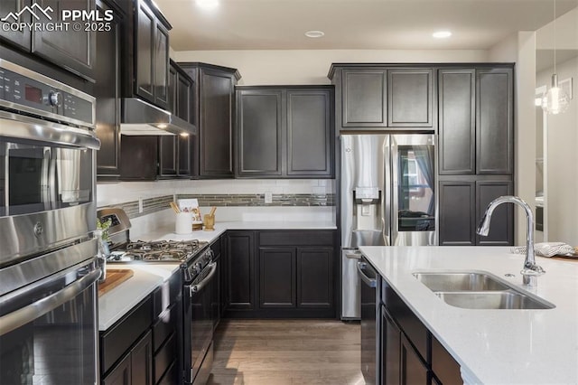 kitchen featuring light stone countertops, sink, pendant lighting, stainless steel appliances, and dark hardwood / wood-style floors