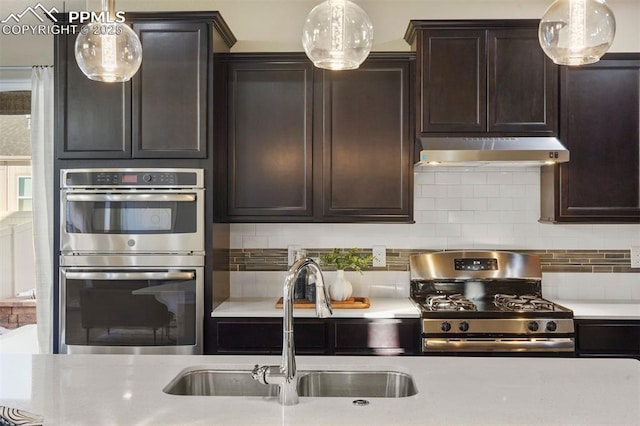 kitchen featuring pendant lighting, appliances with stainless steel finishes, sink, tasteful backsplash, and dark brown cabinetry