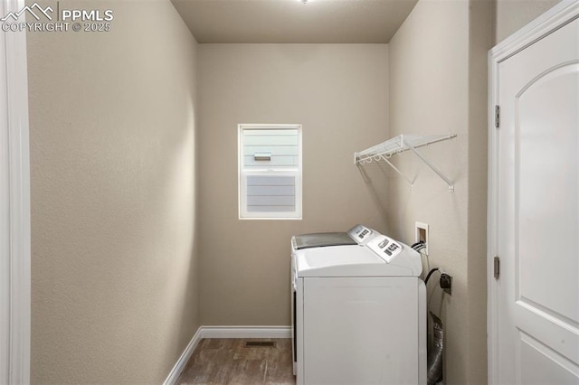 clothes washing area with washer and dryer and hardwood / wood-style flooring